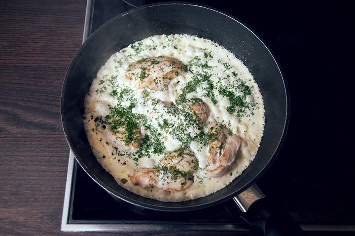 Chicken fillet on a frying pan in mayonnaise sauce with herbs